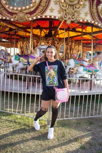 Model posing with the Sakura (pink and white) candy bag in front of a carousel.